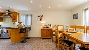 A kitchen with a dining area, wooden cabinets, a stove, and a window with blinds. - 5 bedroom accommodation in llanafan/Aberystwyth (llanafan/Aberystwyth)