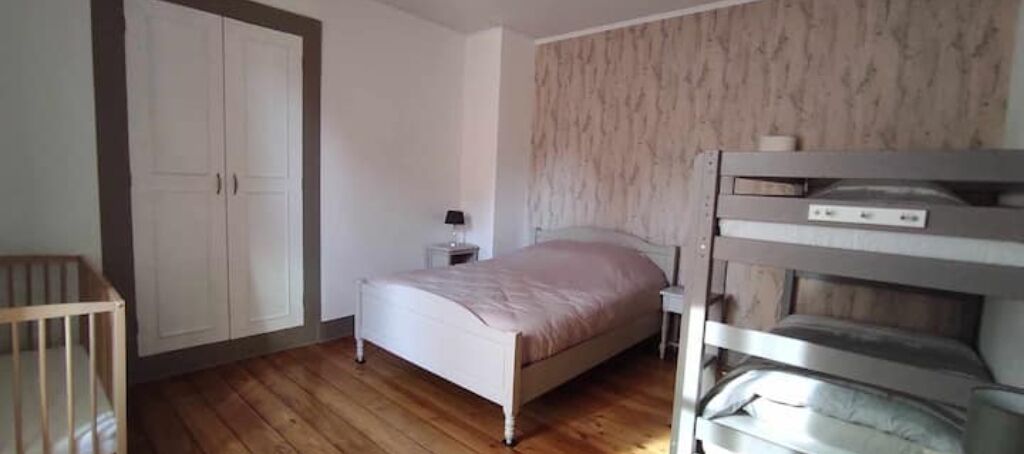 Ein Schlafzimmer mit einem Bett, einem Nachttisch, einem Kleiderschrank und einem Stockbett.