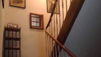 Un escalier en bois, avec des balustrades blanches, menant à un palier.