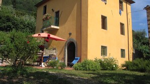 A two-story building with a yellow facade, a balcony with a wrought iron railing, and a red umbrella. - A stunning property with beautiful views across the valley towards Lucca (Guzzano)