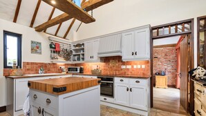 Una cocina con armarios blancos, encimera de madera y pared de ladrillo.