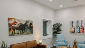 A modern living room with a brown leather sofa, a blue armchair, and a coffee table. There are two paintings on the walls, a ceiling fan, and a potted plant. -  Downtown Loft 
Cozy 1-bedroom apartment in adorable Aberdeen with WiFi (Aberdeen)