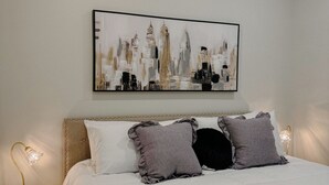 A bedroom with a large bed, a headboard, and a cityscape painting on the wall. -  Downtown Loft 
Cozy 1-bedroom apartment in adorable Aberdeen with WiFi (Aberdeen)
