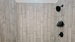 A shower with a herringbone tile pattern and a pebble mosaic floor. -  Downtown Loft 
Cozy 1-bedroom apartment in adorable Aberdeen with WiFi (Aberdeen)
