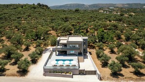 A modern two-story house with a rooftop pool and outdoor seating area, surrounded by dense vegetation and hills in the background. - Aura Del Sol (Zakynthos)