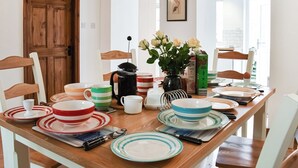 Une table à manger dressée avec différents plats, une cafetière et un vase rempli de fleurs.