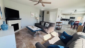 A living room with a sofa, a coffee table, a TV, and a fireplace.