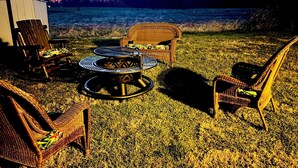 A patio with wicker furniture, a round table, and a fire pit.