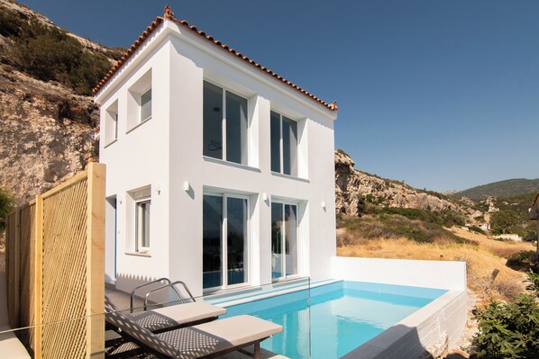 A modern two-story house with a swimming pool, large windows, and a view of the surrounding landscape. - Kontemare Seascape (Samos)