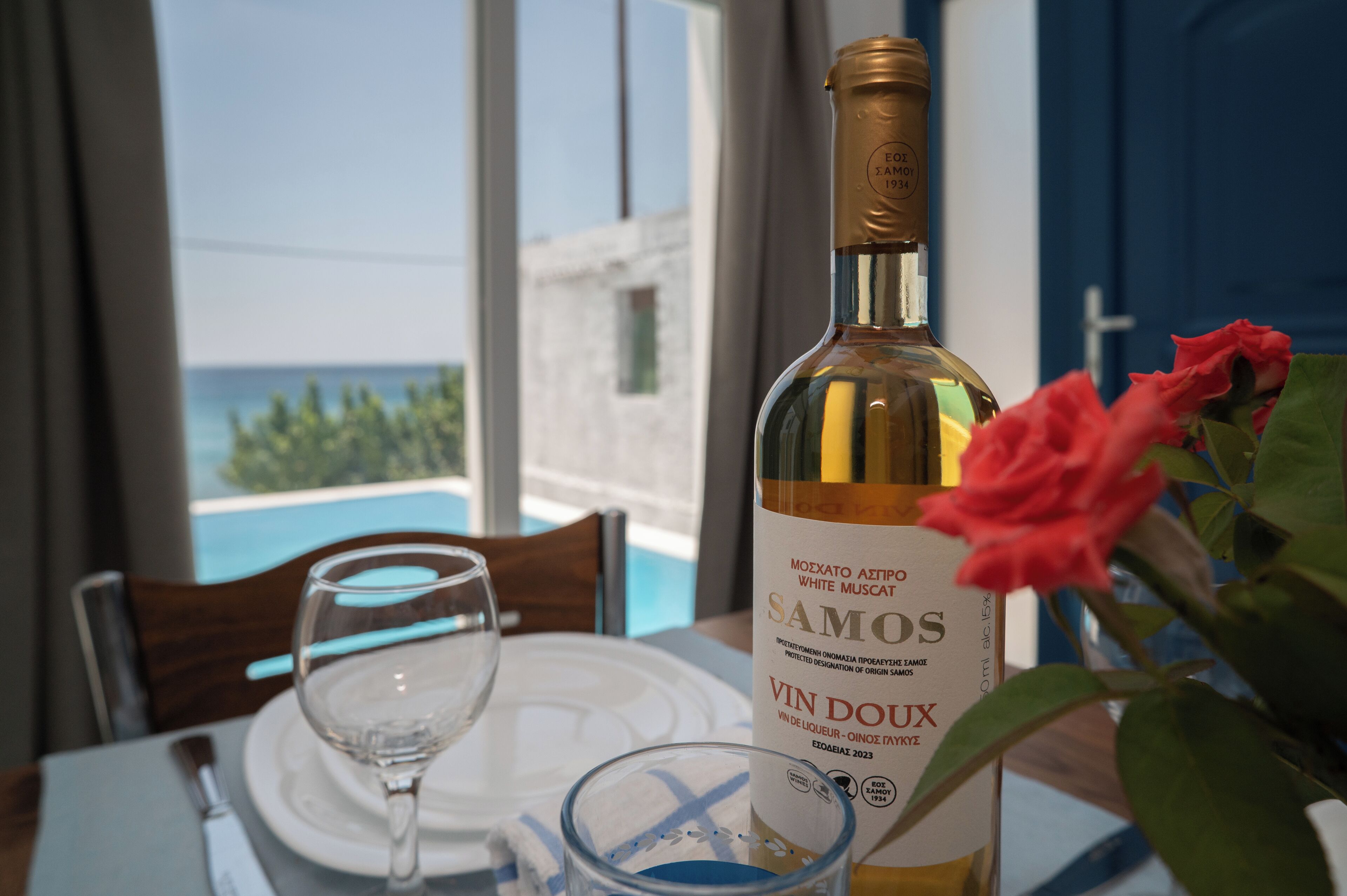 Une table avec une bouteille de vin, un verre et une rose.
