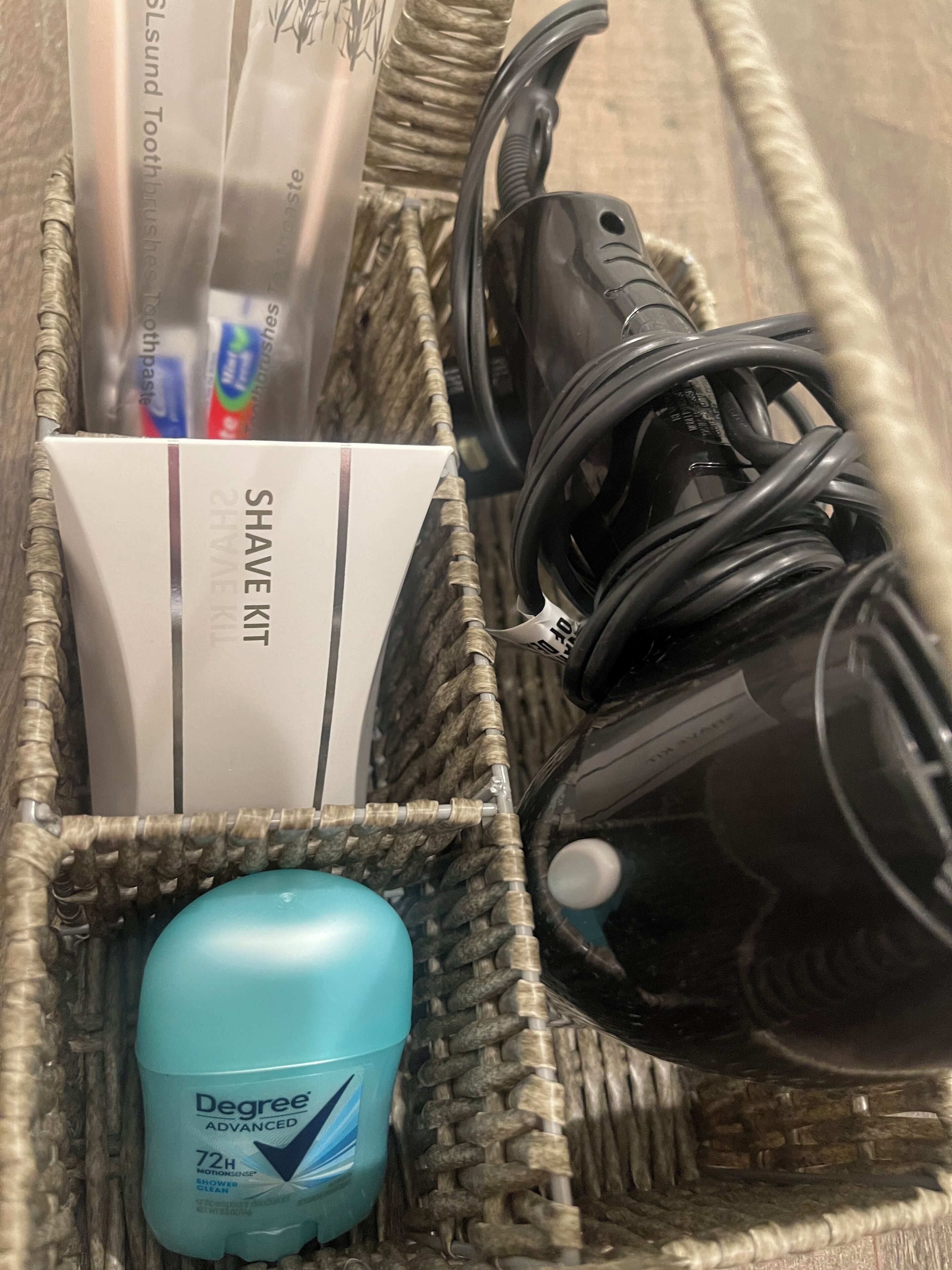 A wicker basket containing a blue bottle of Degree Advanced 72H shower gel, a white box labeled "SHAVE KIT," and a black hairdryer.