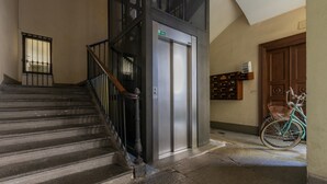 A staircase leading to an elevator, a bicycle, and a wooden door. - La Corte by Wonderful Italy (Turin)