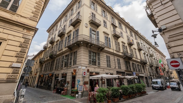A historic building with multiple balconies, a cobblestone street, and outdoor seating for cafes. - La Corte by Wonderful Italy (Turin)