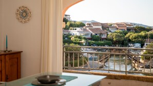 Uitzicht vanaf een balkon op een rivier met boten, een brug en huizen op de achtergrond.