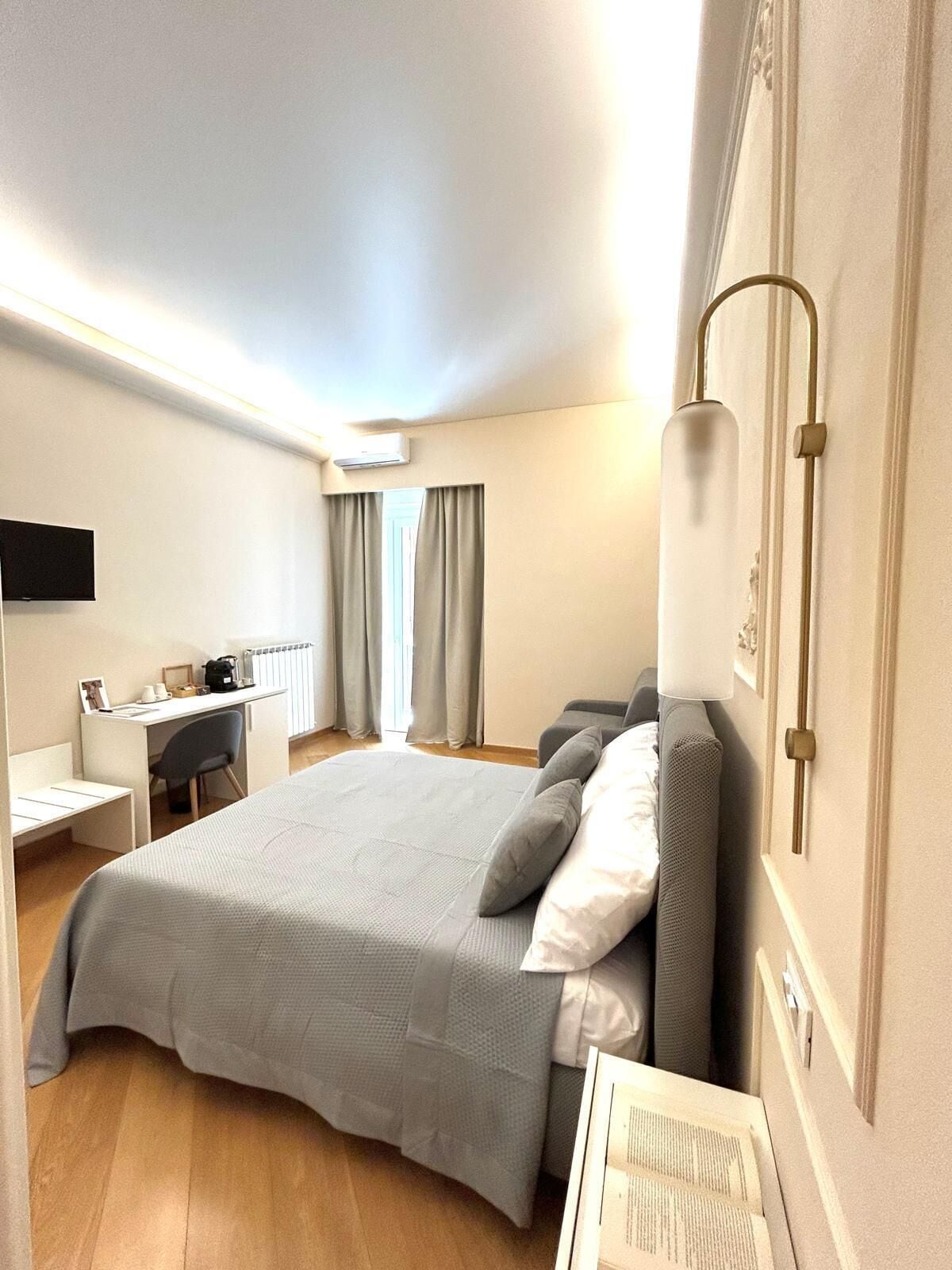 A hotel room with a bed, a desk, a chair, and a TV.