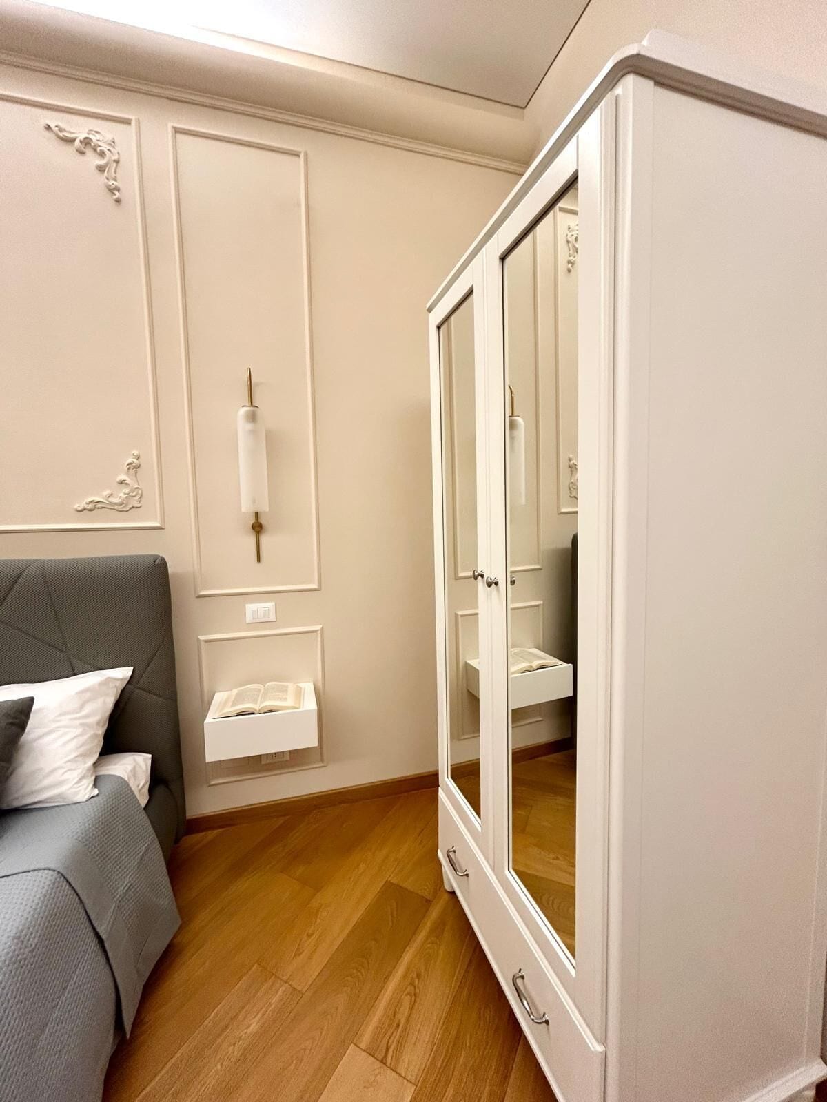 A bedroom with a bed, a wardrobe, and a mirror.
