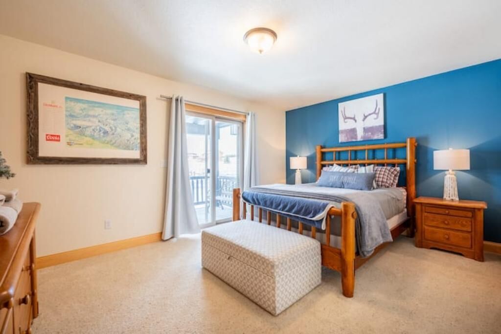 A bedroom with a bed, bedside tables, a window, and a door.