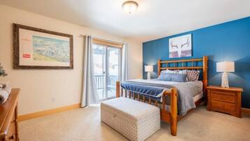 A bedroom with a bed, bedside tables, a window, and a door.