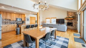A spacious kitchen with wooden cabinets, a dining area with a checkered rug, and a cozy living room with a fireplace.