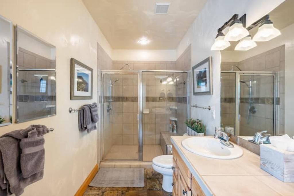 A modern bathroom with a glass-enclosed shower, a large sink, and a mirror.