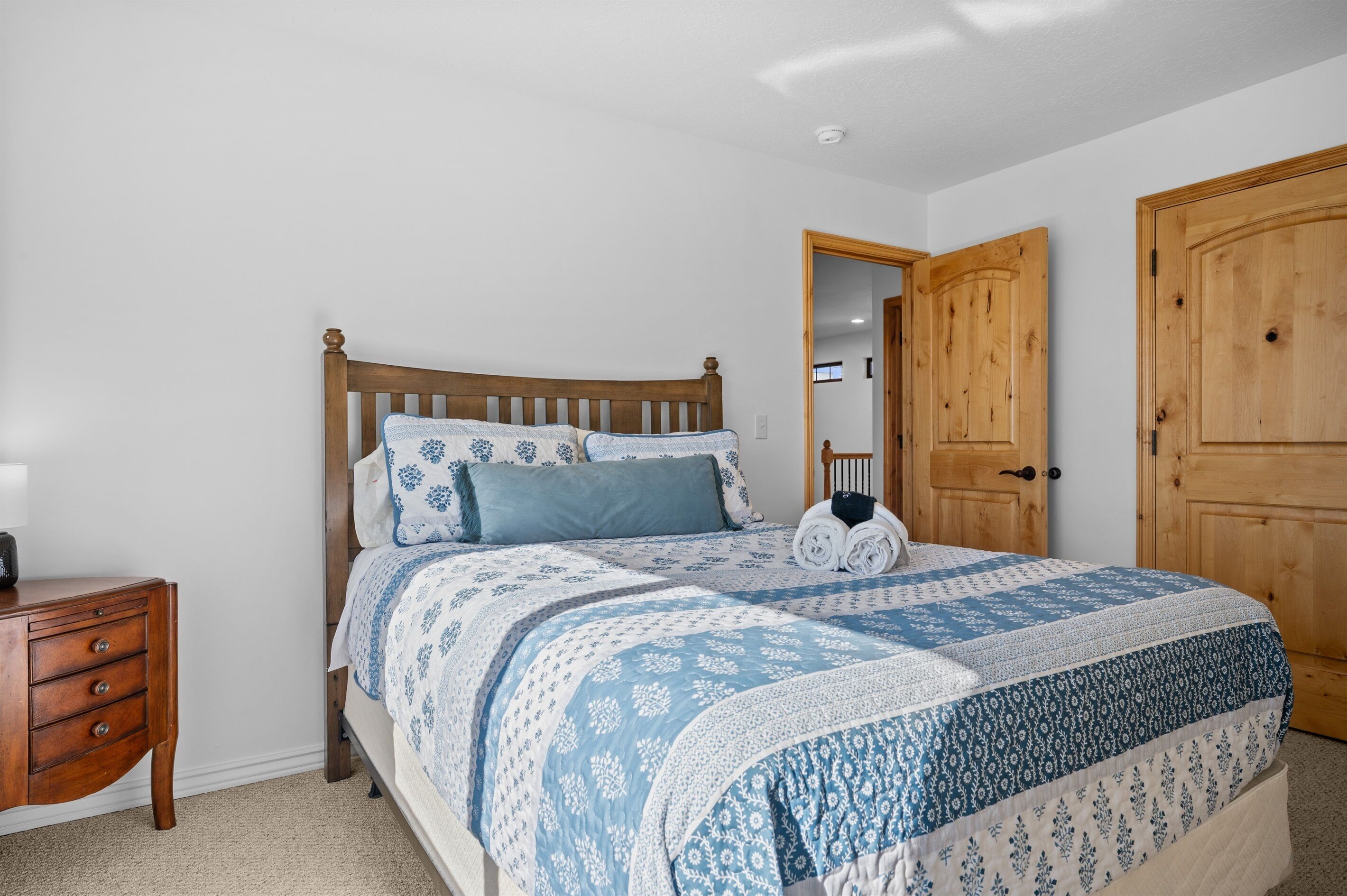 A bedroom with a wooden bed, a nightstand, and a wardrobe.