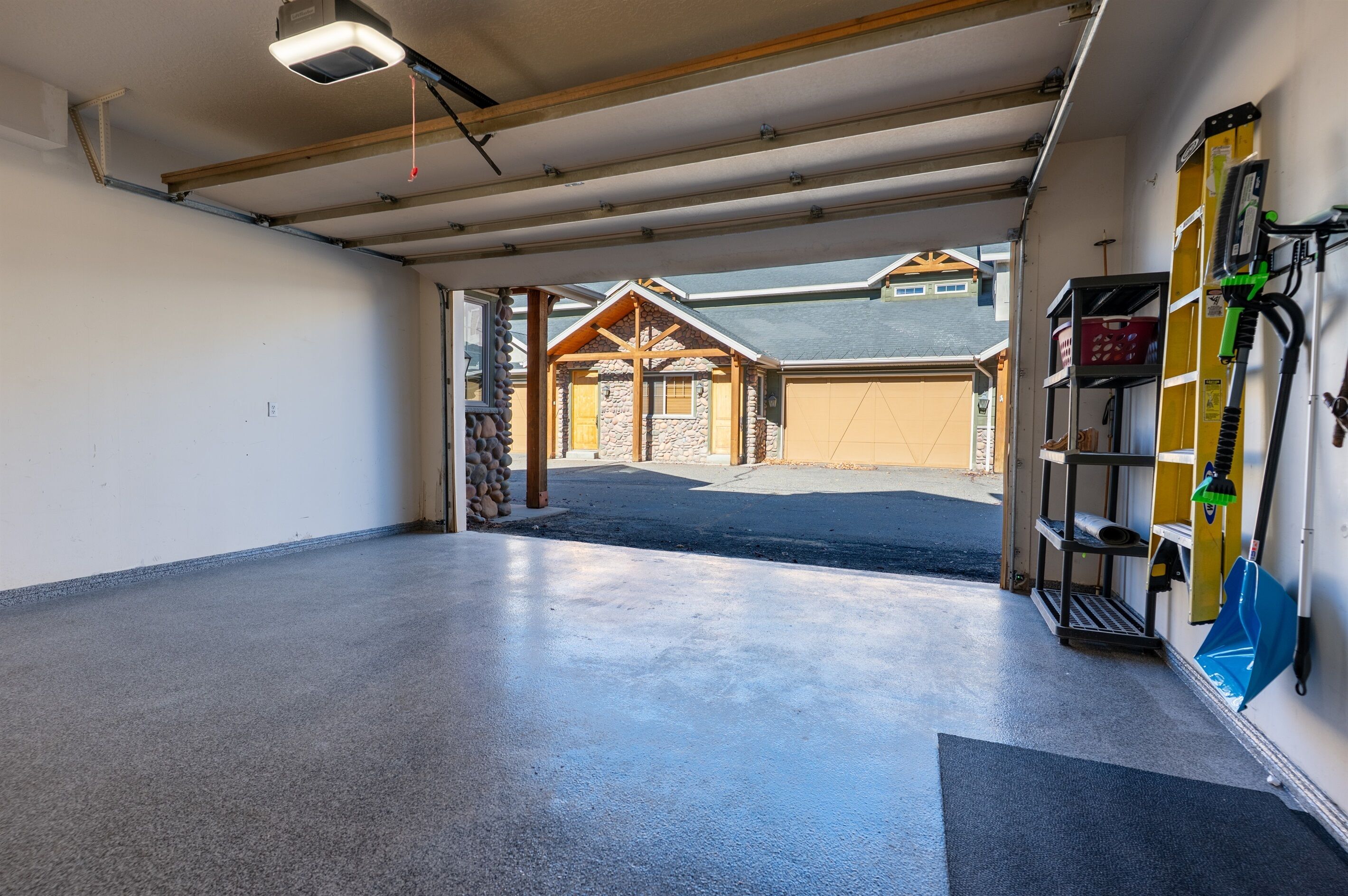 A garage with a concrete floor, a wooden ceiling, and a stone wall.