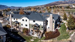 A multi-story house with a stone facade, multiple balconies, and a well-maintained lawn. - Moonbeam Retreat C505 |By Powder Mtn Ski Resort (Eden)