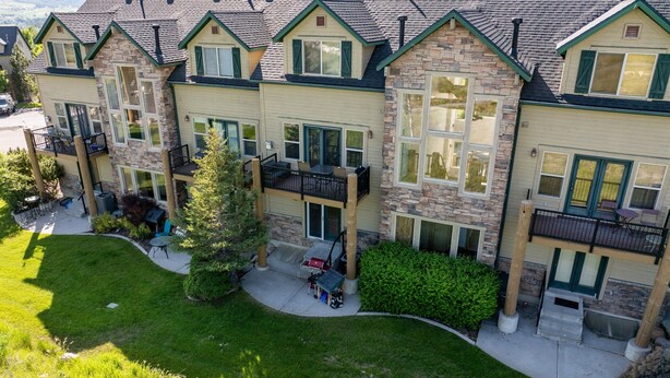 A multi-story residential building with a stone facade, green shutters, and a covered outdoor seating area. - Eden Mtn Retreat MH207 | Near Powder Mtn | Hot Tub (Eden)