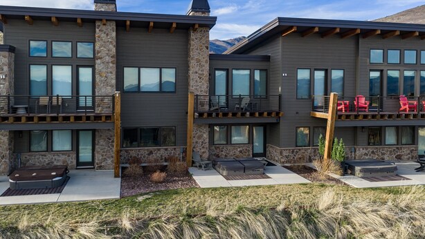 A modern multi-story building with stone and wood accents, large windows, and outdoor seating areas. - Moose Ridge Hideaway Ri903 | Ski Retreat | Hot Tub (Eden)