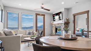 A living room with a fireplace, a TV mounted above it, and a dining area with a round table. - Moose Ridge Hideaway Ri903 | Ski Retreat | Hot Tub (Eden)