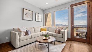 A living room with a sectional sofa, a round coffee table, and a large sliding glass door to the outdoors. - Moose Ridge Hideaway Ri903 | Ski Retreat | Hot Tub (Eden)
