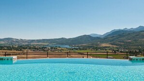 A swimming pool with clear blue water, surrounded by a wooden fence, and a mountainous landscape in the background. - Moose Ridge Hideaway Ri903 | Ski Retreat | Hot Tub (Eden)