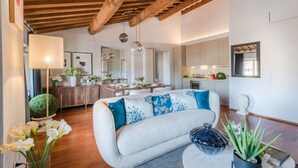 A modern living room with a sofa, a dining area, and a kitchen.