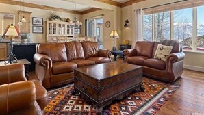 A spacious living room with leather sofas, a coffee table, and a large window offering a view of the outdoors. - Powder Mtn Wolf Den TR11|Mtn Biking |Dog Friendly (Eden)