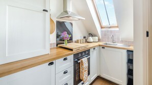 A modern kitchen with white cabinetry, a wooden countertop, a skylight, and a view of the sky. - We love the views from the garden across open countryside. (Seaton, near Hornsea)