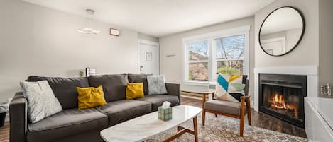 A modern living room with a gray sofa, a white coffee table, and a fireplace.