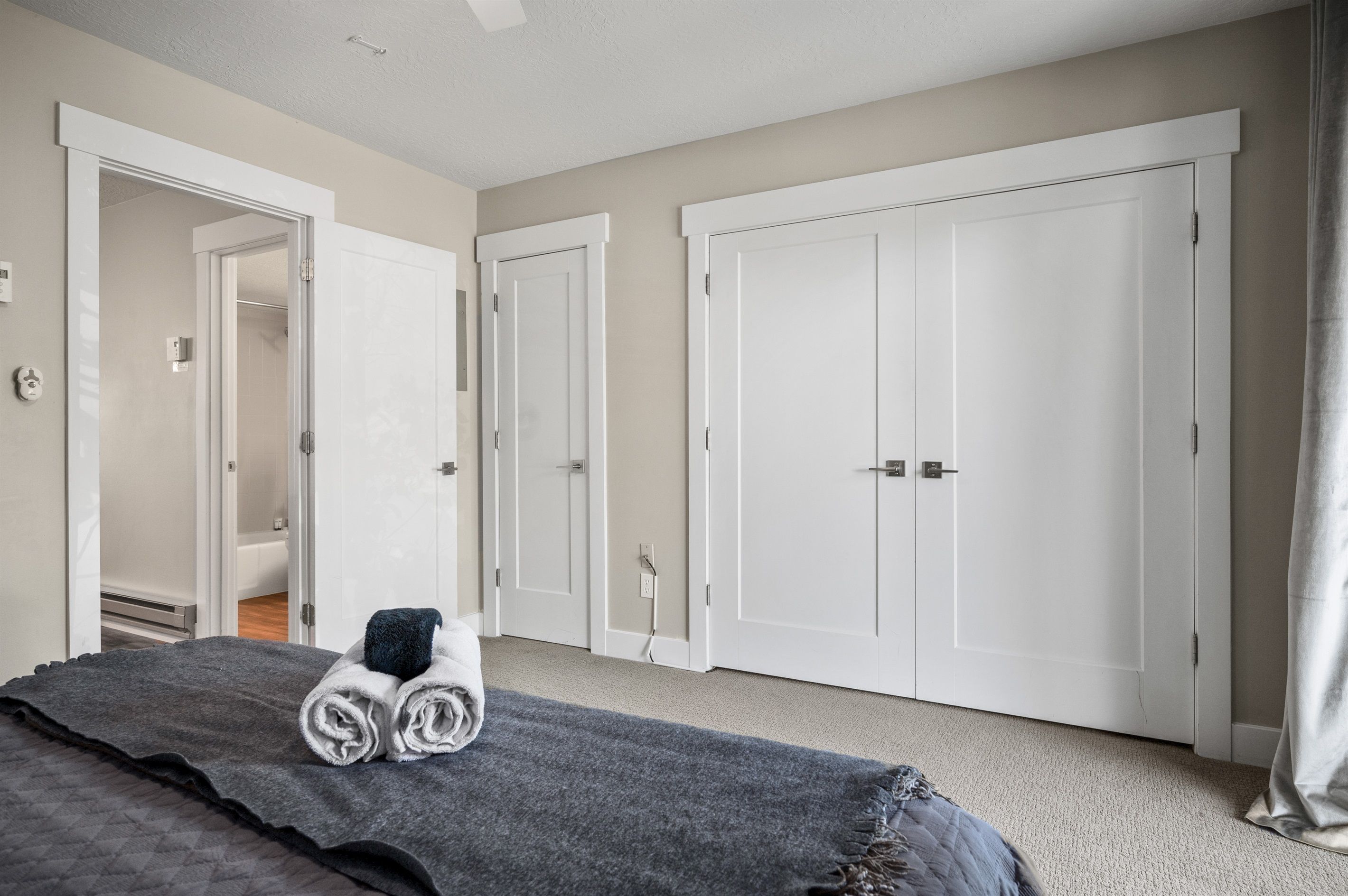 A hotel room with a bed, a bathroom, and two white wardrobes.