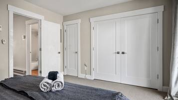 A hotel room with a bed, a bathroom, and two white wardrobes.