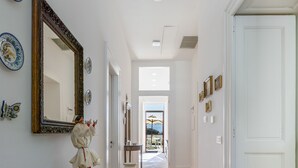 A hallway with a wooden console table, a large mirror, and a door at the end. - Villa Fienga - Maison Edvige 8 beds (Meta)