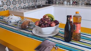 A kitchen with a yellow countertop, a bowl of fruit, a coffee maker, and a striped tablecloth. - Villa Fienga - Maison Edvige 8 beds (Meta)
