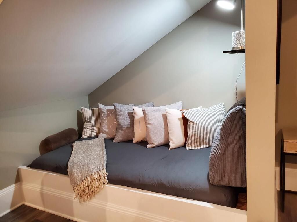 A cozy loft bedroom with a built-in bench bed, a hanging light fixture, and a small shelf with a decorative item.