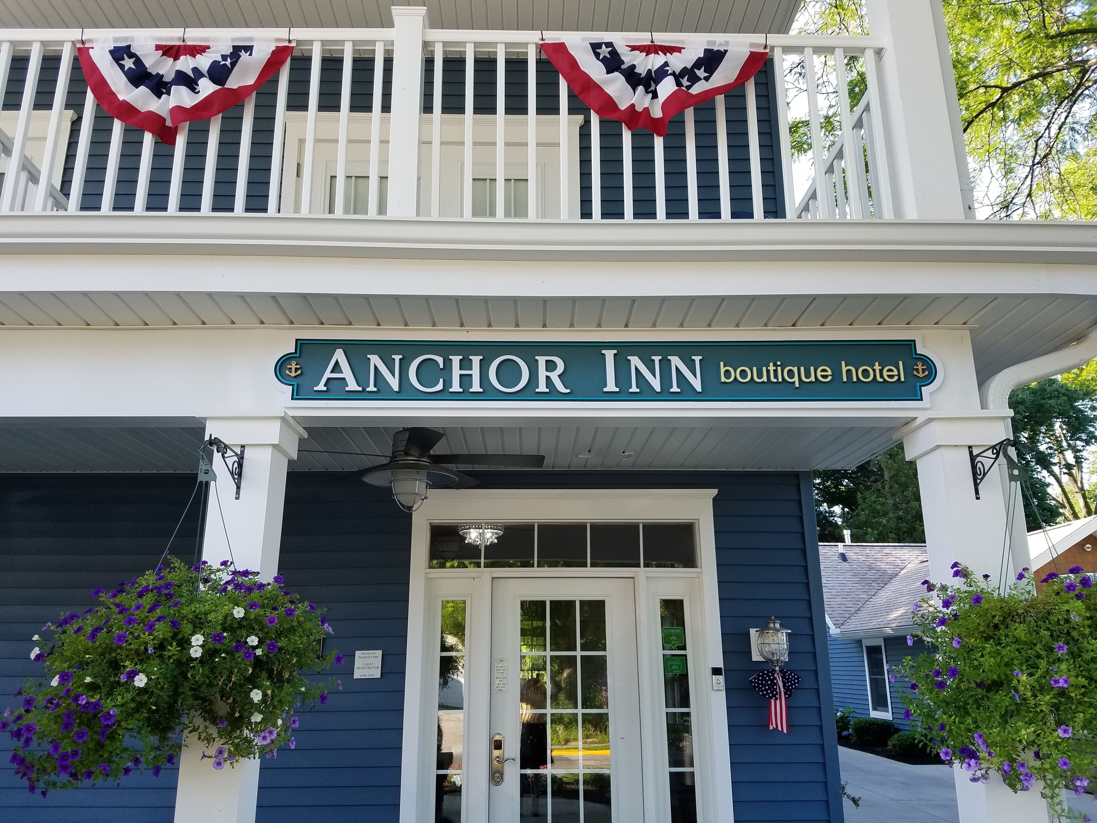 Exterior del hotel boutique Anchor Inn, con un balcón adornado con guirnaldas de banderas estadounidenses.