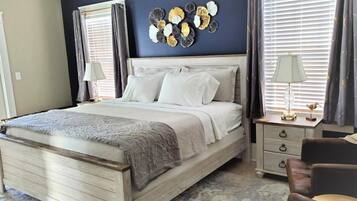 Een slaapkamer met een houten bed, twee nachtkastjes, een stoel en een decoratief wandobject.