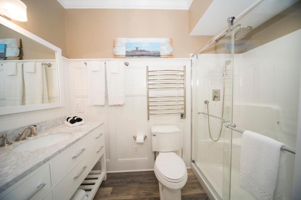 A modern bathroom with a glass shower enclosure, a white toilet, and a marble sink.