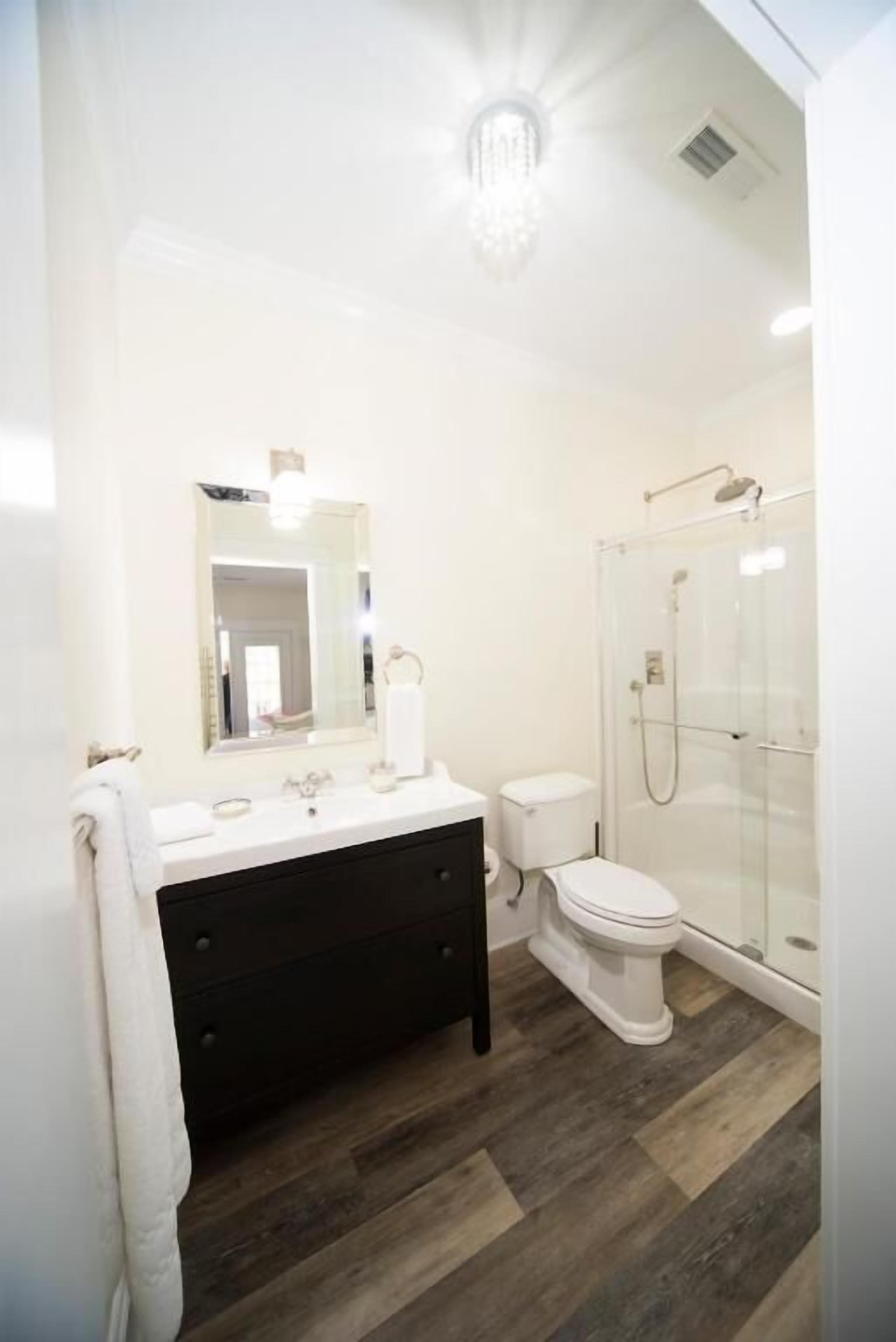 A bathroom with a white vanity, a glass shower enclosure, and a white toilet.