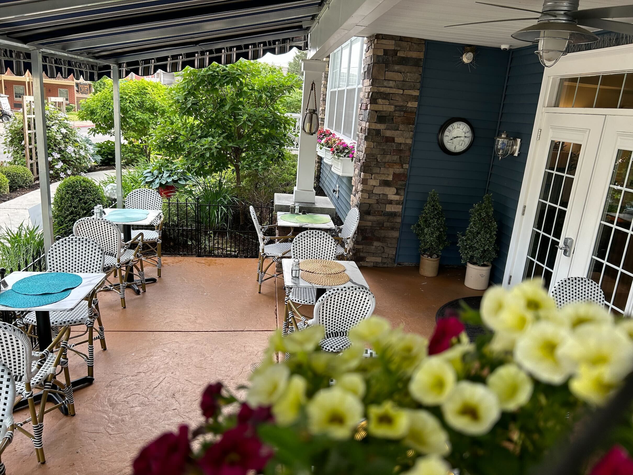 Une terrasse extérieure avec des meubles en osier et une horloge au mur.