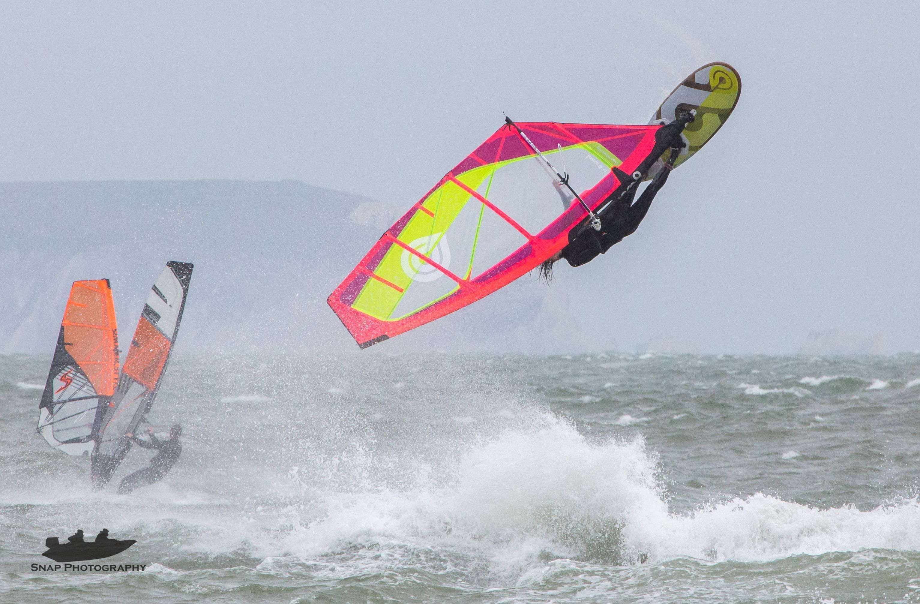 Uma pessoa praticando windsurf com uma vela colorida no oceano.