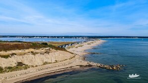 Une zone côtière caractérisée par une plage de sable, une côte rocheuse et un ciel bleu dégagé.