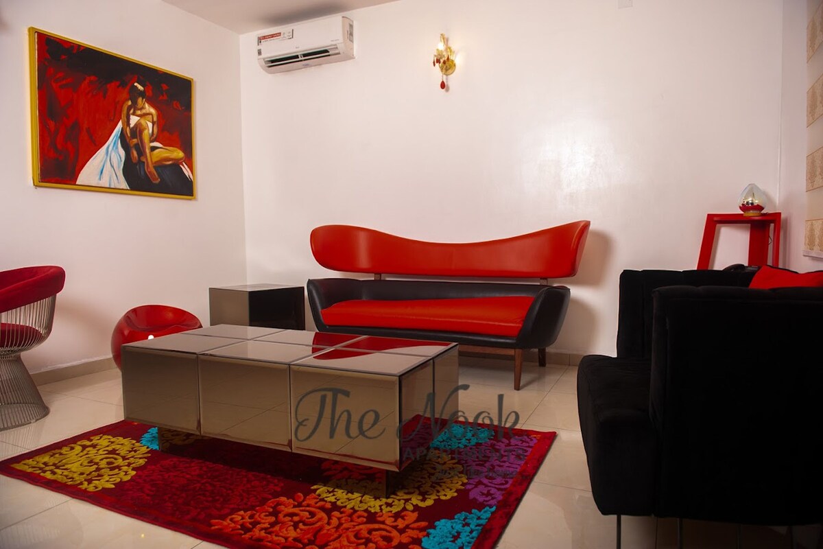 A living room with a red sofa, a black armchair, a coffee table, and a colorful rug.