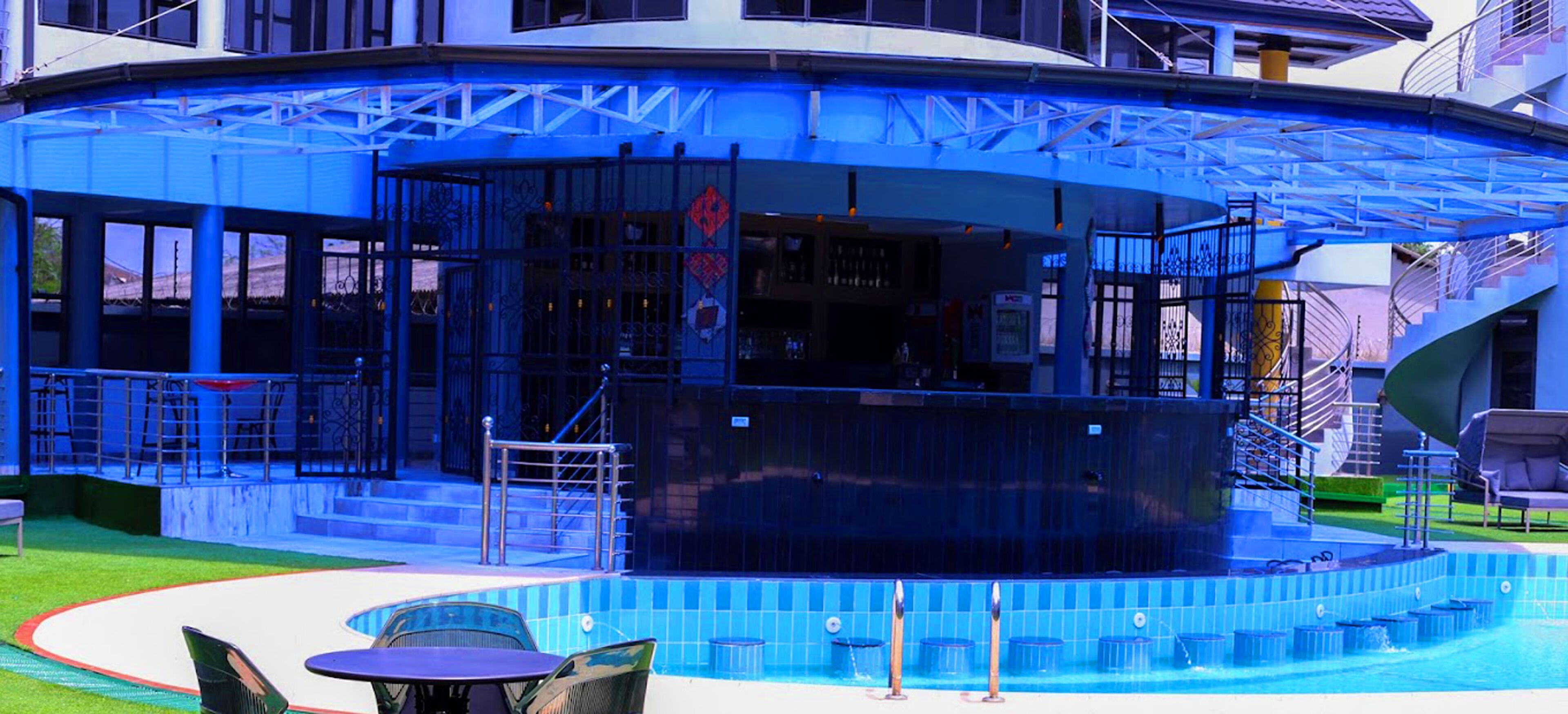 Un área de piscina con bar, asientos al aire libre y una escalera que conduce a un nivel superior.